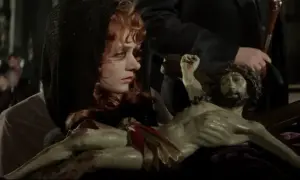 Marianna lalka, z czarną chustą na głowie, trzyma w ramionach figurę Chrystusa.
