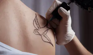 Tatuaż jaskółki, symbol wolności i nadziei, powstaje na skórze.