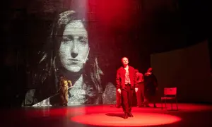 Na scenie, w świetle czerwonych reflektorów, stoi mężczyzna. W tle projekcja przedstawia twarz matki Cezarego Baryki.