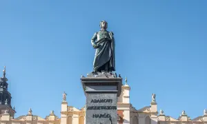 Pomnik Adama Mickiewicza, symbol romantyczności, na tle błękitnego nieba i zabytkowych kamienic.