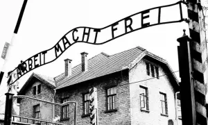 Brama z napisem "Arbeit Macht Frei" nad budynkami obozu. To miejsce symbolizuje tragedię holocaustu.