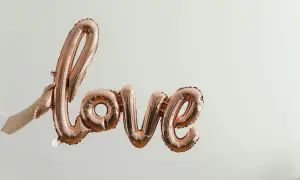 Różowe balony w kształcie napisu "Love" unoszą się w powietrzu. To symbol bezwarunkowej miłości matki do dziecka, jak w pięknych cytatach.