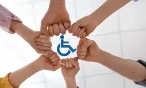 Dłonie tworzą krąg wokół symbolu niepełnosprawności. To znak solidarności i wsparcia dla osób z niepełnosprawnościami.