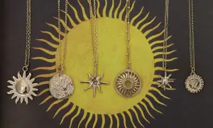 Sześć złotych naszyjników z wisiorkami w kształcie słońca i twarzy, wiszących na tle stylizowanego symbolu słońca.