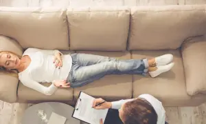 Kobieta leży na kozetce, opowiadając o swoich problemach, a terapeuta notuje. Może to być początek terapii, gdzie odkrywa swoje kompleksy, niczym **Edyp** odkrywający prawdę o sobie.