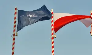 Flaga NATO i biało-czerwona flaga Polski powiewają na tle błękitnego nieba. Dwa państwa NATO razem.