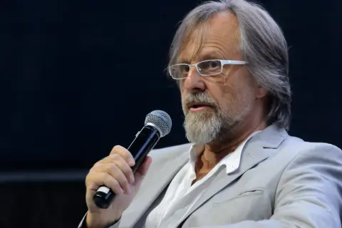 Mężczyzna w okularach i jasnej marynarce trzyma mikrofon. Człowiekiem jestem i nic co ludzkie nie jest mi obce, nawet gdy przemawiam do tłumu.