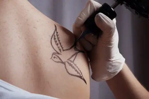 Tatuaż jaskółki, symbol wolności i nadziei, powstaje na skórze.