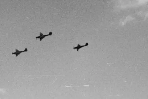 Trzy samoloty Luftwaffe w formacji lecące na tle nieba.