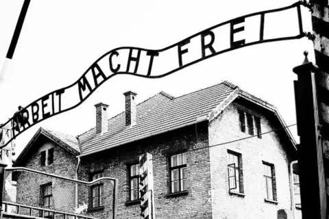 Brama z napisem "Arbeit Macht Frei" nad budynkami obozu. To miejsce symbolizuje tragedię holocaustu.