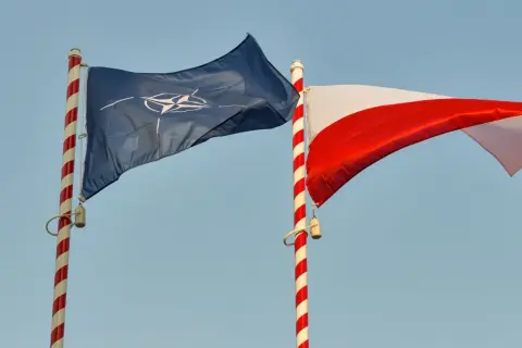 Flaga NATO i biało-czerwona flaga Polski powiewają na tle błękitnego nieba. Dwa państwa NATO razem.