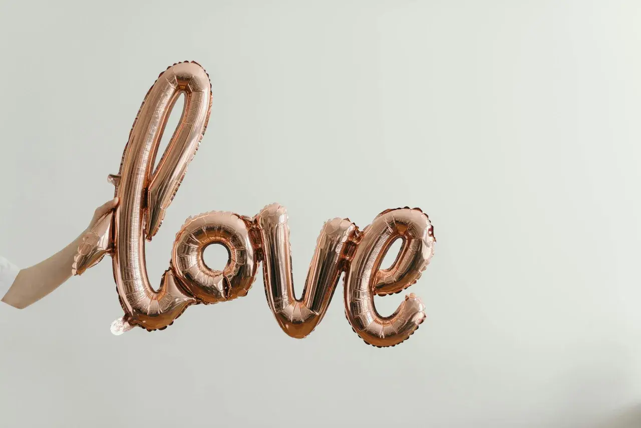 Różowe balony w kształcie napisu "Love" unoszą się w powietrzu. To symbol bezwarunkowej miłości matki do dziecka, jak w pięknych cytatach.