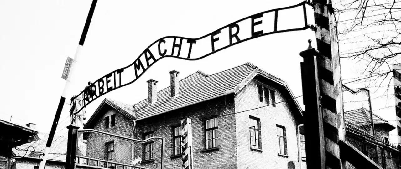 Brama z napisem "Arbeit Macht Frei" nad budynkami obozu. To miejsce symbolizuje tragedię holocaustu.