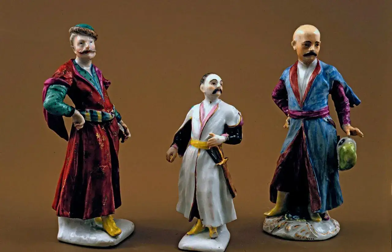 Trzy porcelanowe figurki przedstawiające szlachciców w strojach z epoki. Jeden z nich, dumny sarmata, ma na sobie bogato zdobiony kontusz.
