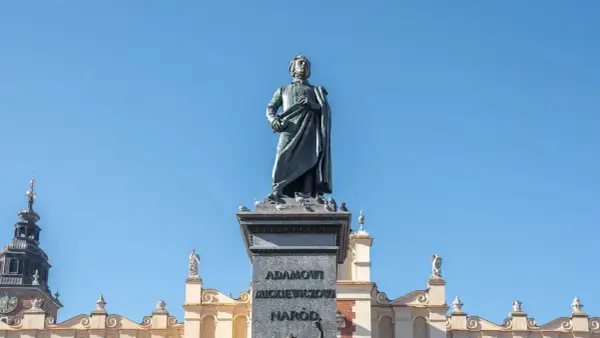 Pomnik Adama Mickiewicza, symbol romantyczności, na tle błękitnego nieba i zabytkowych kamienic.