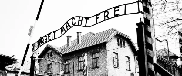 Brama z napisem "Arbeit Macht Frei" nad budynkami obozu. To miejsce symbolizuje tragedię holocaustu.